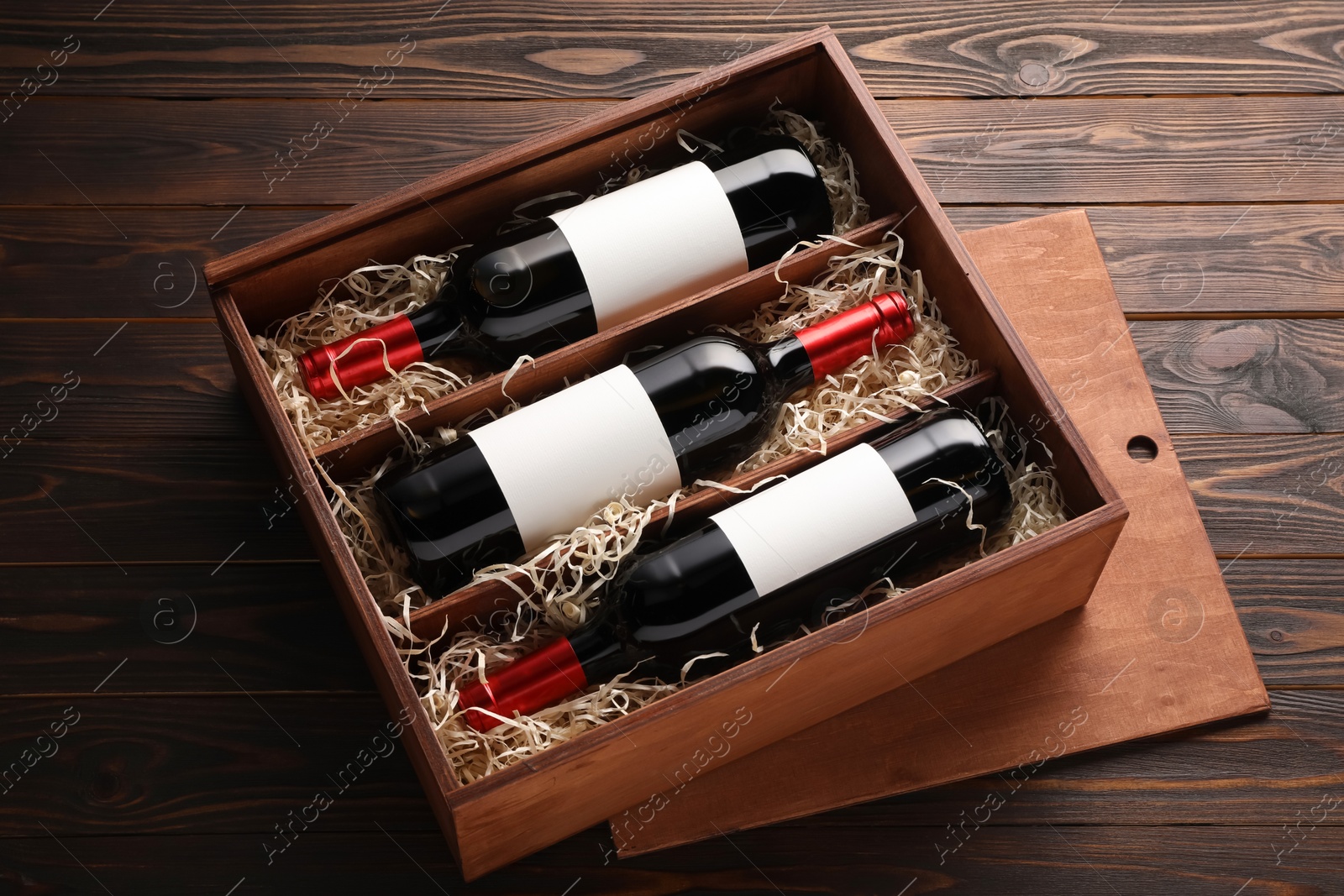 Photo of Box with wine bottles on wooden table, above view
