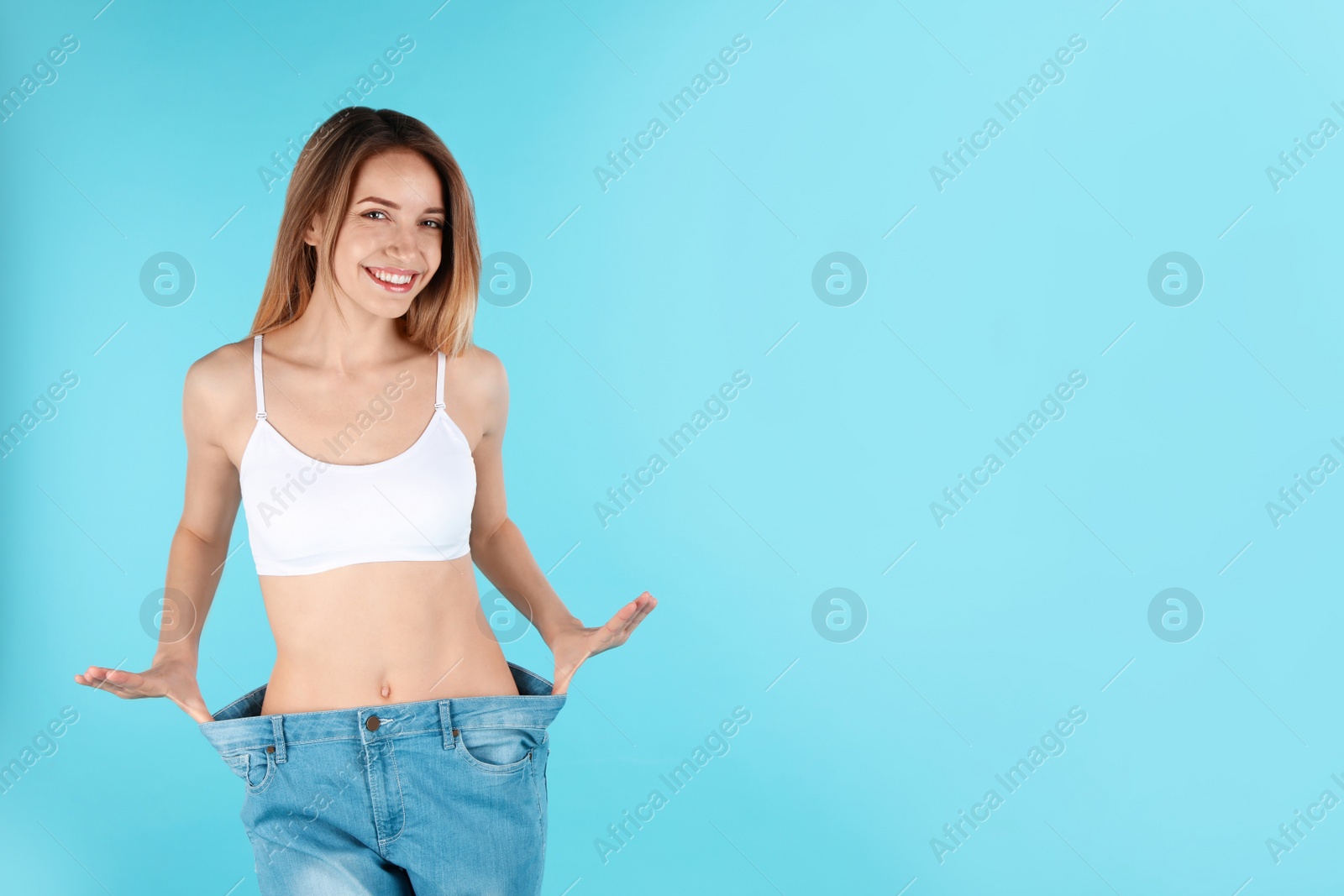 Photo of Slim woman in oversized jeans on color background, space for text. Perfect body