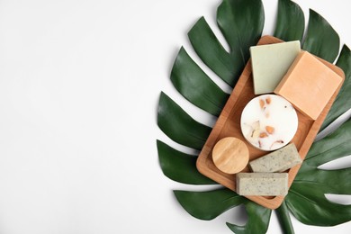 Photo of Wooden tray with eco friendly personal care products and green leaf on white background, top view. Space for text