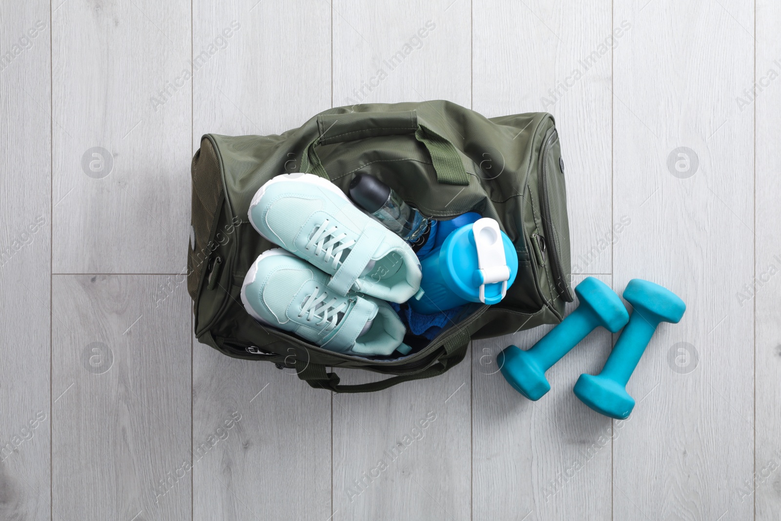 Photo of Sports bag with gym stuff and equipment on white floor, flat lay