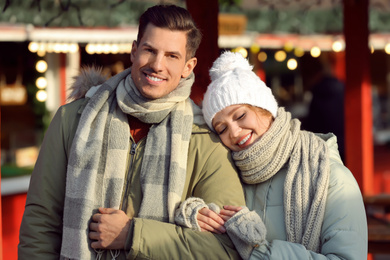 Happy couple in warm clothes at winter fair. Christmas season