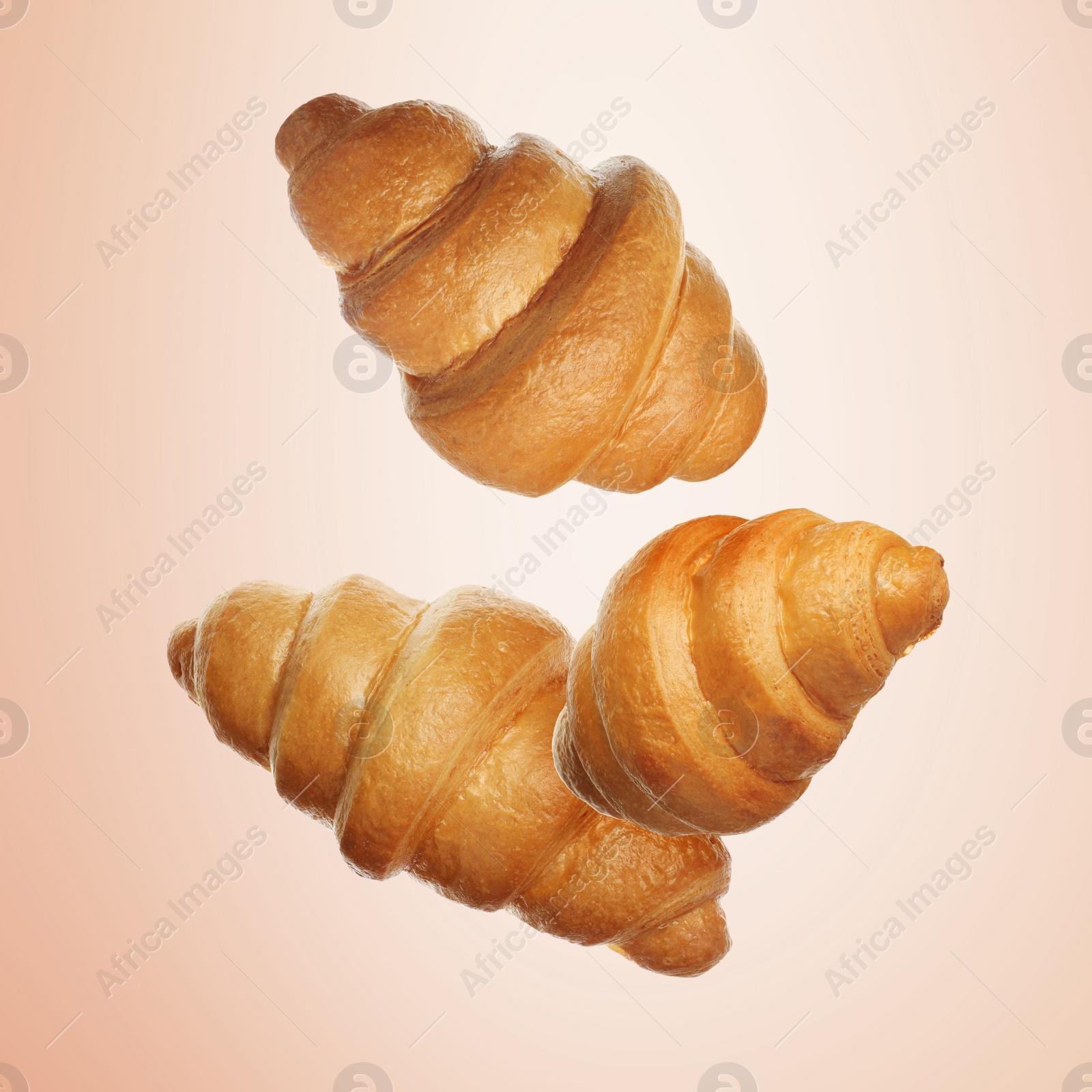 Image of Golden croissants falling on coral gradient background