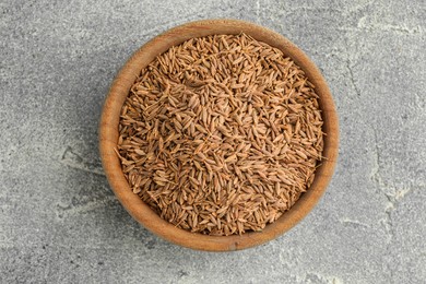 Bowl of caraway seeds on grey table, top view