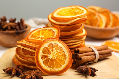 Photo of Dry orange slices, anise stars and cinnamon sticks on wooden board, closeup