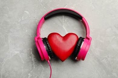 Photo of Decorative heart with modern headphones on color background, top view