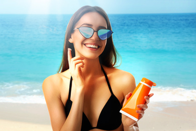 Image of Young woman applying sun protection cream at beach