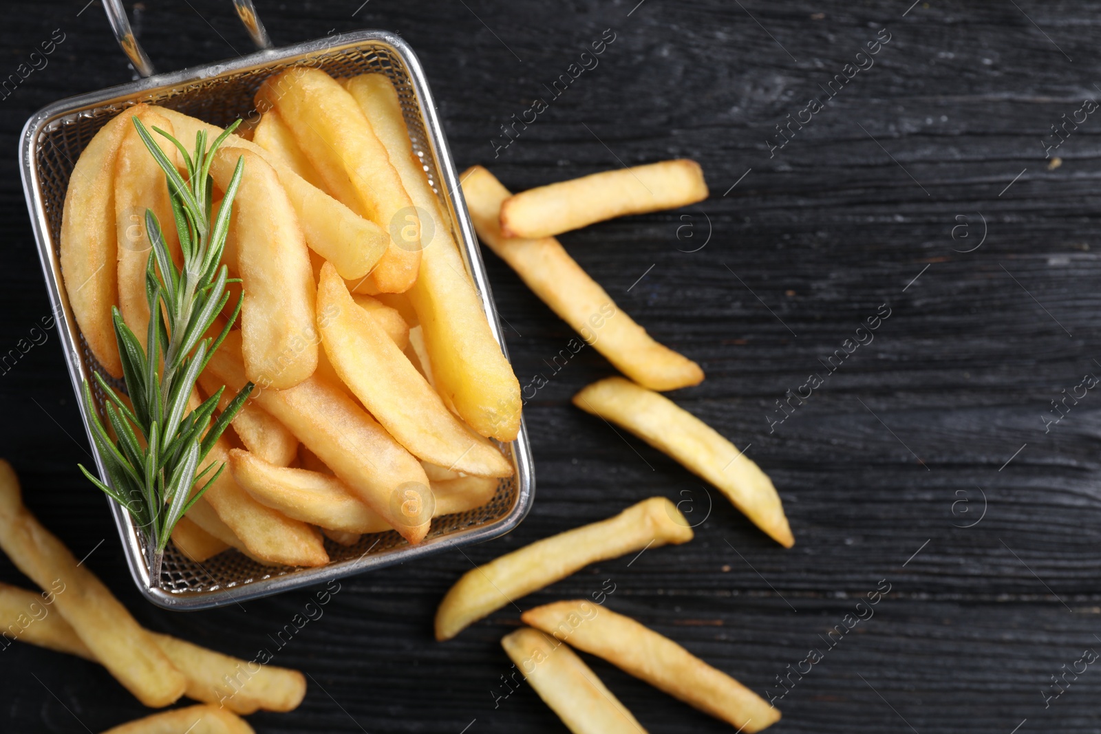 Photo of Tasty french fries with rosemary on dark wooden table, flat lay. Space for text