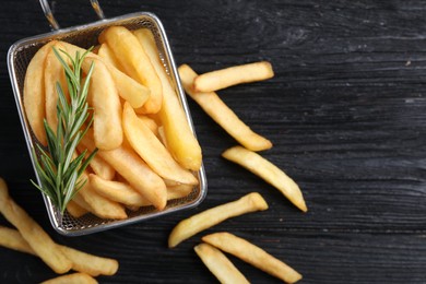 Photo of Tasty french fries with rosemary on dark wooden table, flat lay. Space for text