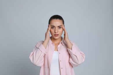 Photo of Young woman suffering from headache on light grey background