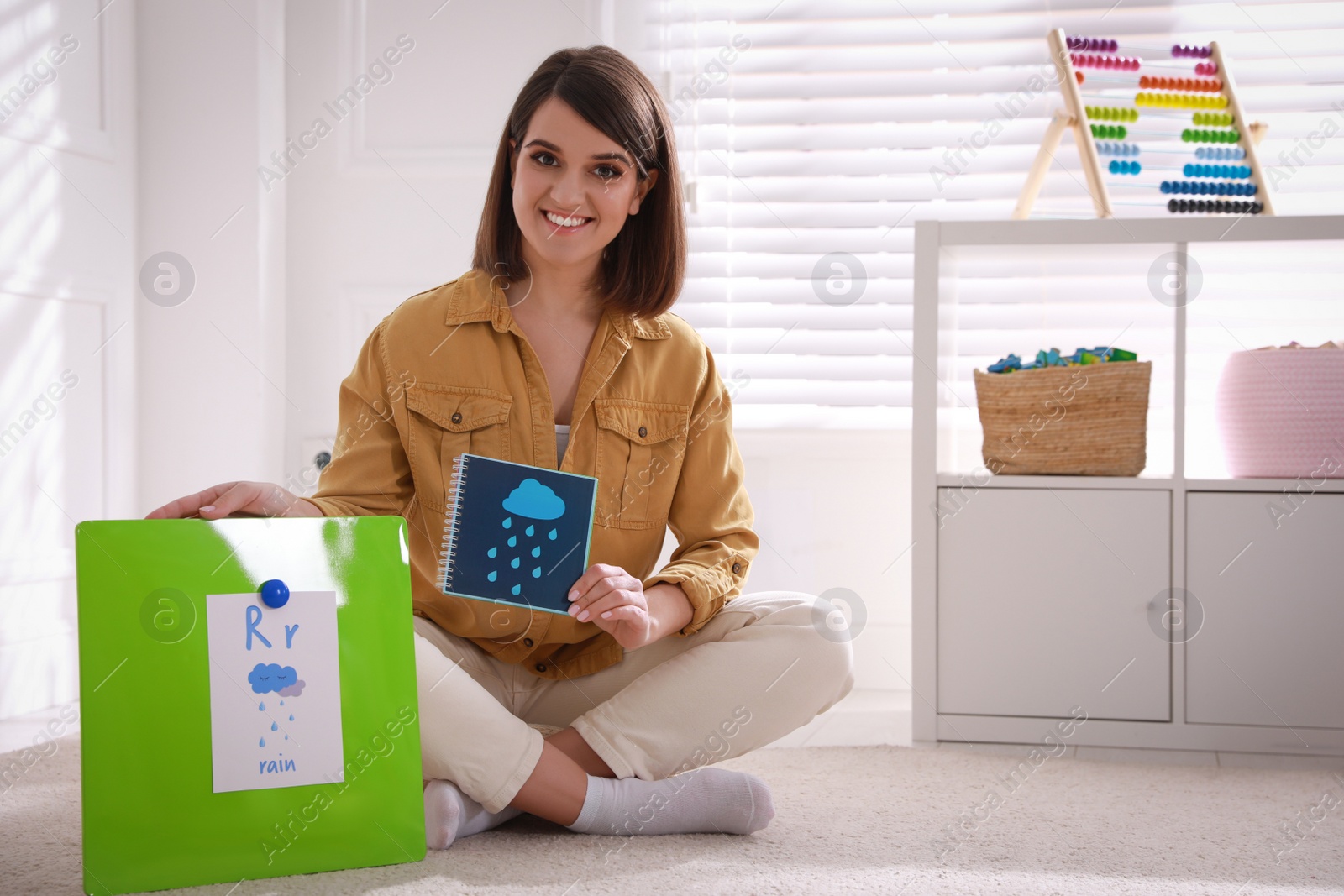 Photo of Happy female English teacher giving lesson indoors. Early childhood education