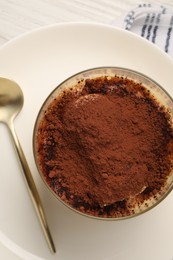 Delicious tiramisu in glass and spoon on table, top view