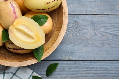 Photo of Fresh ripe pepino melons with leaves on grey wooden table, flat lay. Space for text