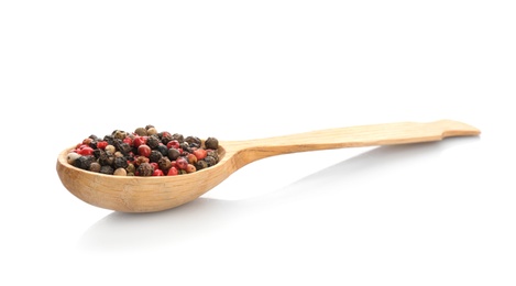 Wooden spoon with different pepper grains on white background