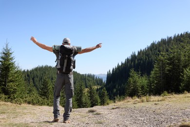 Tourist with backpack in mountains on sunny day, back view. Space for text