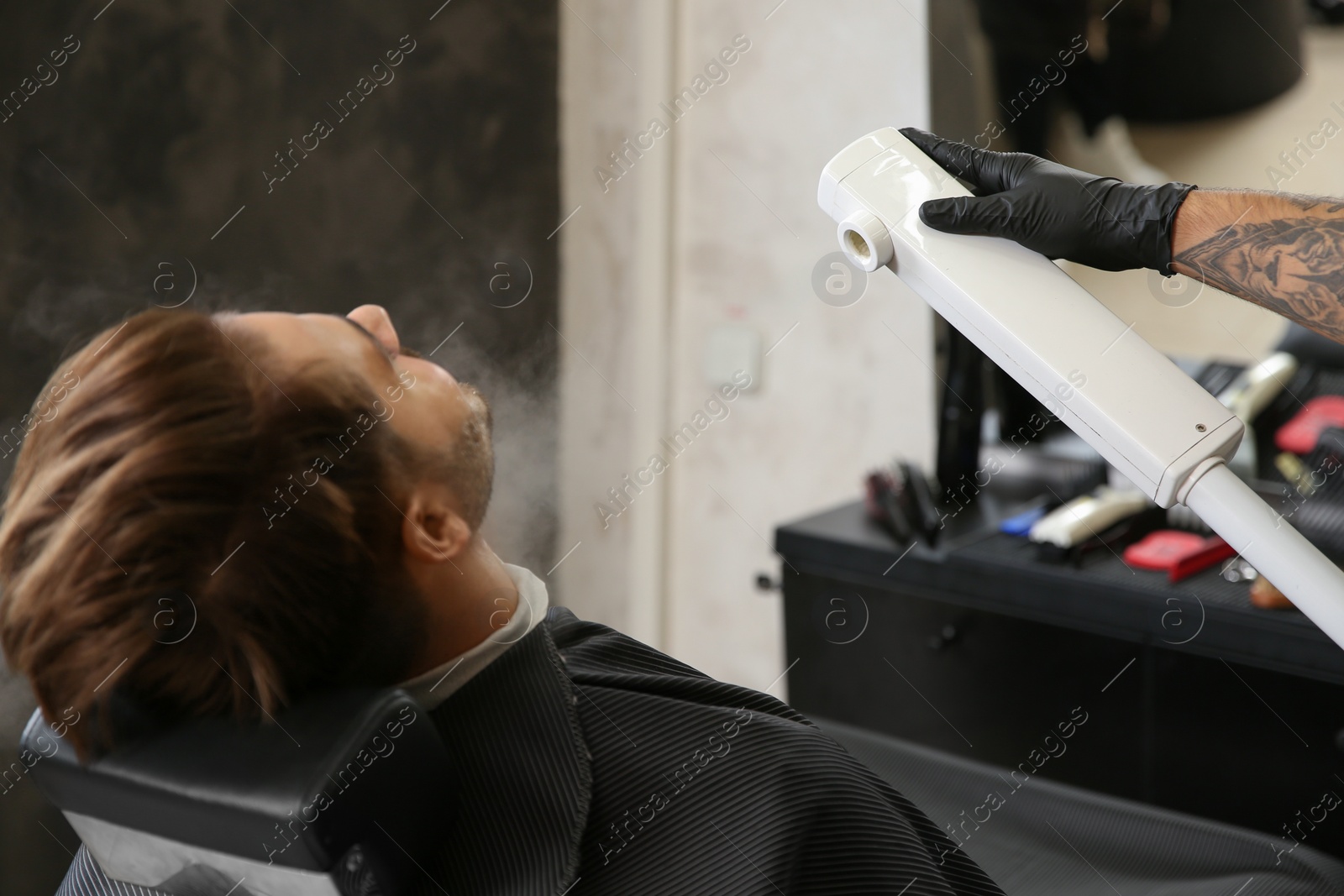 Photo of Hairdresser working with client at barbershop. Professional shaving service