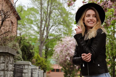Photo of Beautiful young woman wearing stylish hat on spring day, space for text