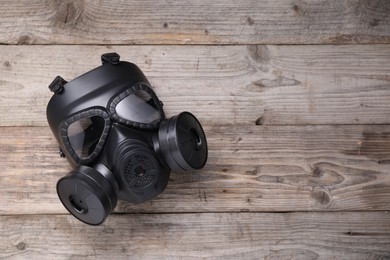 One gas mask on wooden background, top view. Space for text