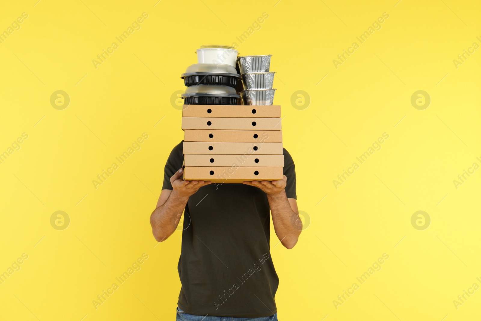 Photo of Young courier with different orders on color background. Food delivery service