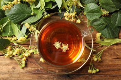 Cup of tea and linden blossom on wooden table, flat lay