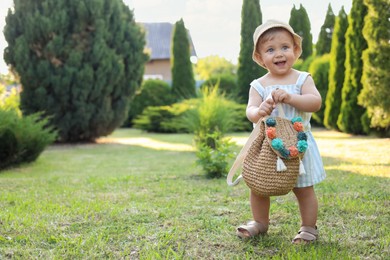 Cute little girl in stylish clothes with knitted backpack outdoors on sunny day. Space for text