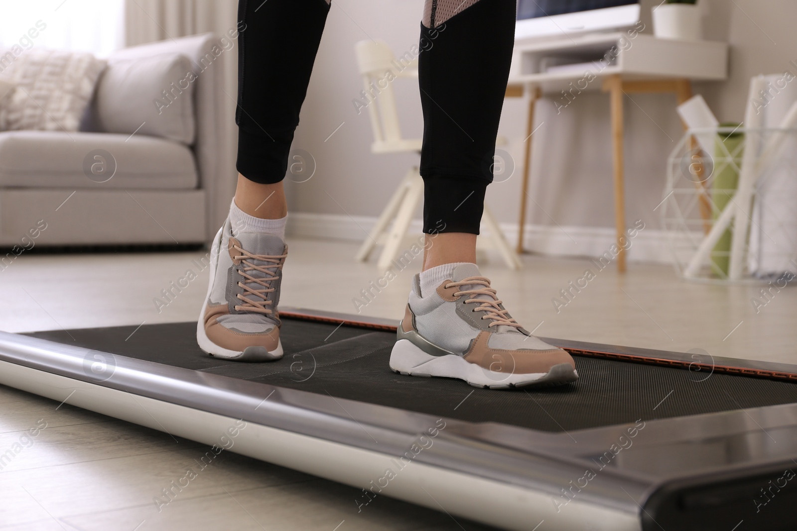 Photo of Woman training on walking treadmill at home, closeup