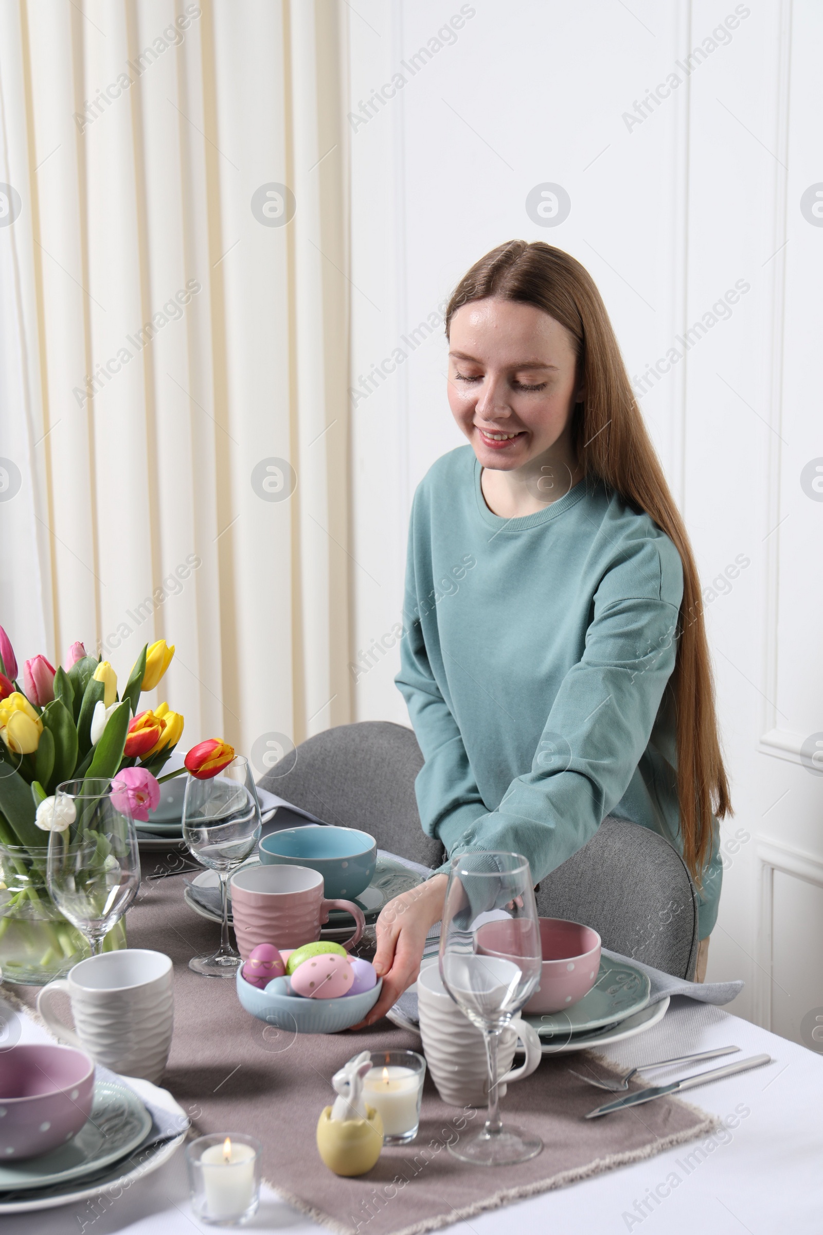 Photo of Woman setting table for festive Easter dinner at home