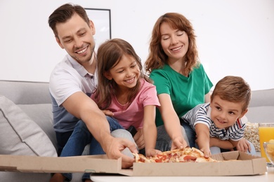 Family eating pizza while watching TV in room