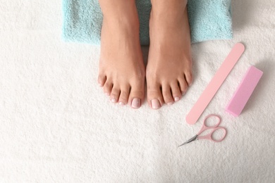 Photo of Top view of woman with beautiful feet and pedicure accessories on white towel, space for text. Spa treatment