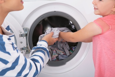 Photo of Little girl helping her mother to do laundry, closeup