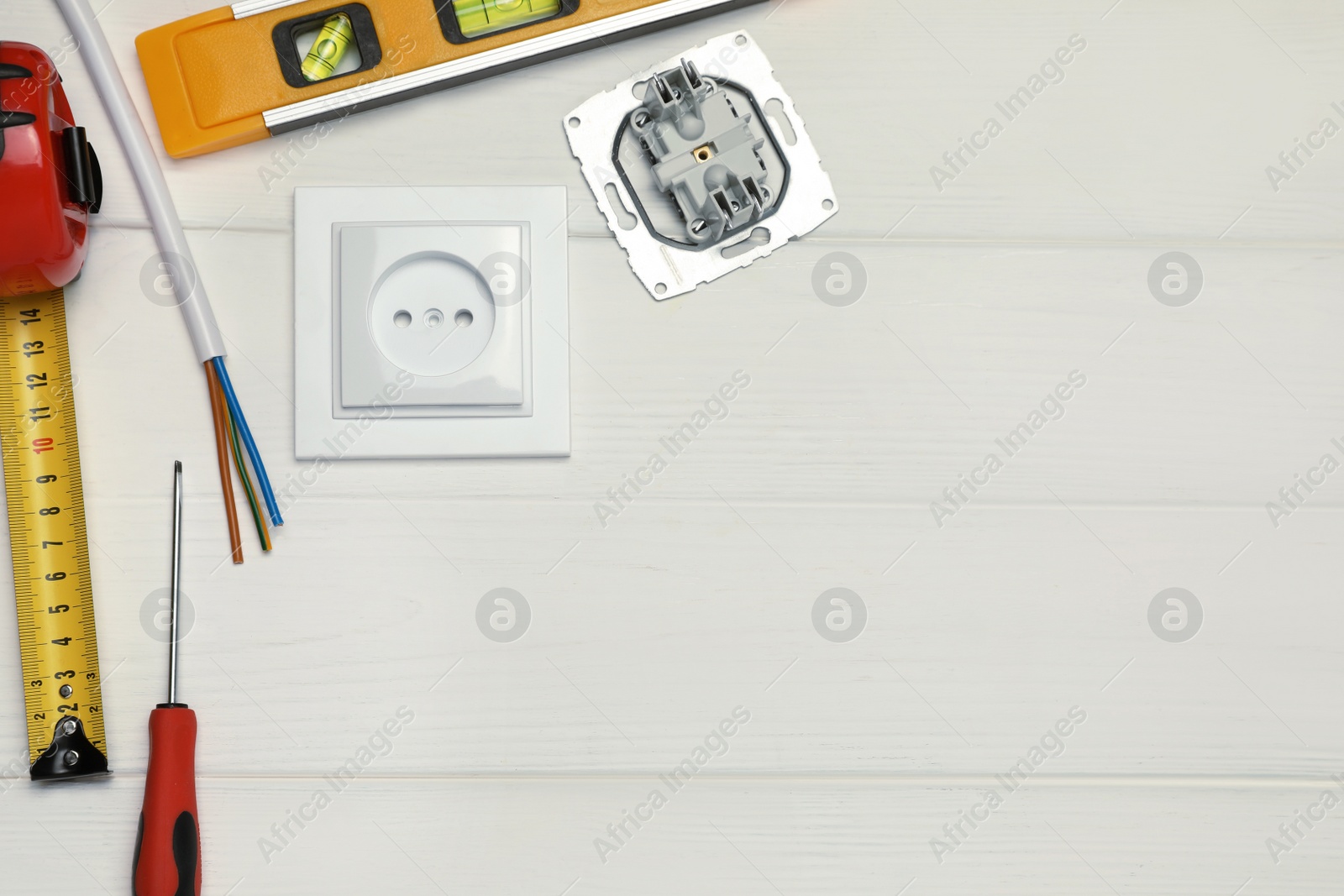 Photo of Power socket and set of electrician's tools on white wooden table, flat lay. Space for text