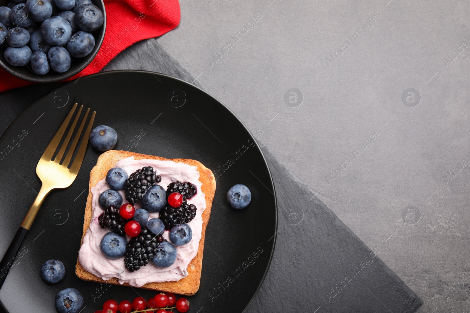 Photo of Tasty sandwiches with cream cheese and berries on grey table, flat lay. Space for text