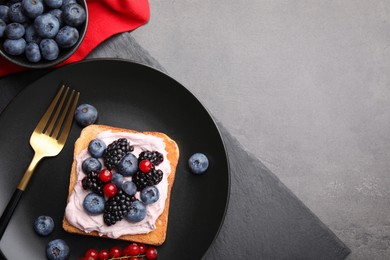 Photo of Tasty sandwiches with cream cheese and berries on grey table, flat lay. Space for text