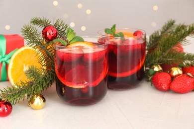 Aromatic Christmas Sangria in glasses and festive decor on white table, closeup