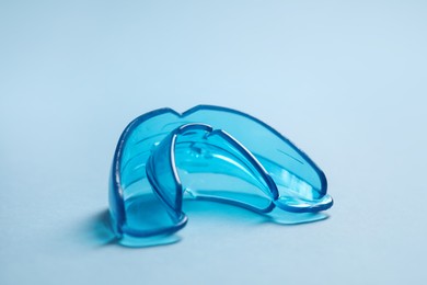 Photo of Dental mouth guard on light blue background, closeup. Bite correction