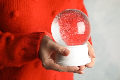 Photo of Woman holding empty snow globe on light background, closeup