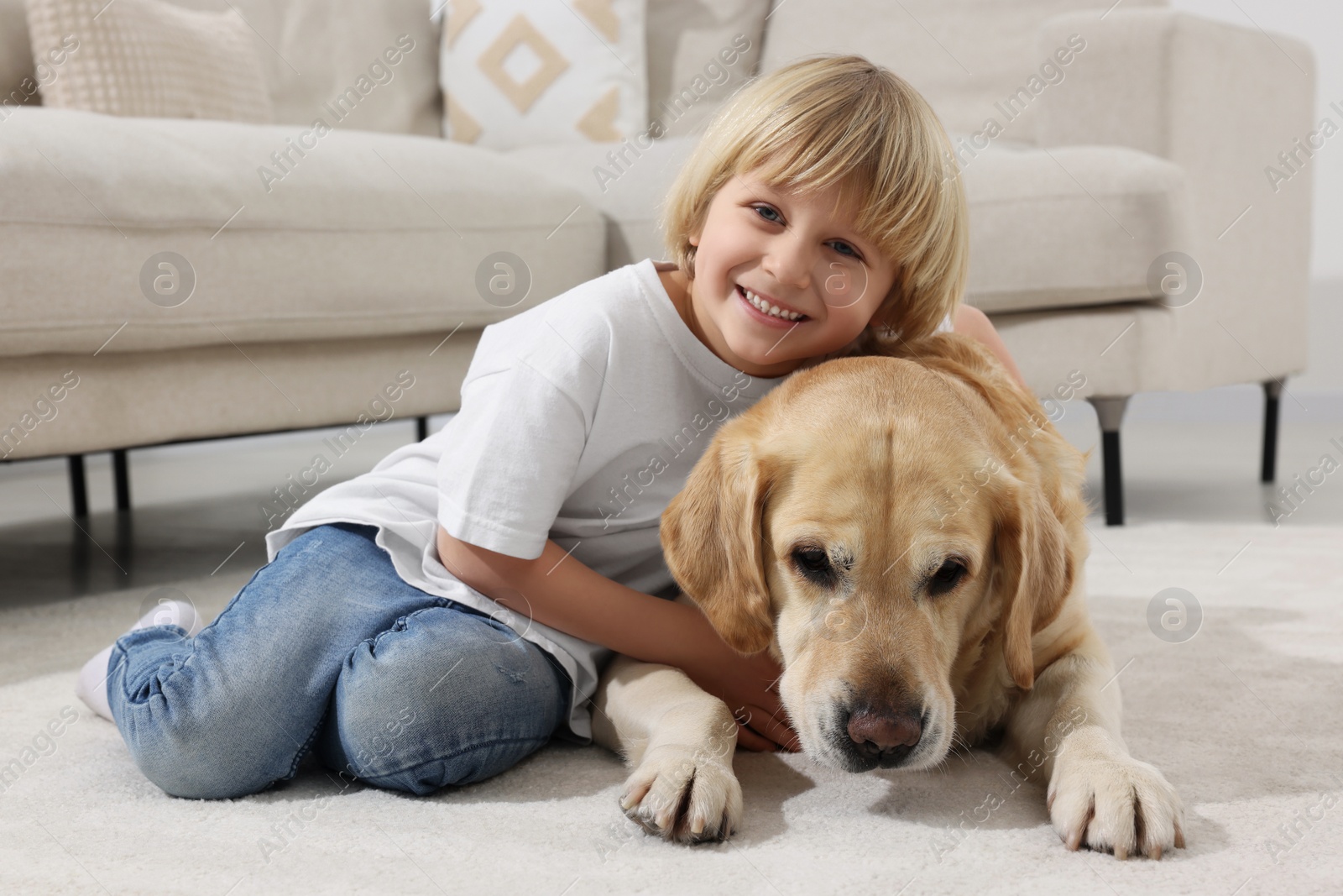 Photo of Cute little child with Golden Retriever on floor at home. Adorable pet