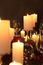 Photo of Christmas celebration. Burning candles, glasses and festive decor on table