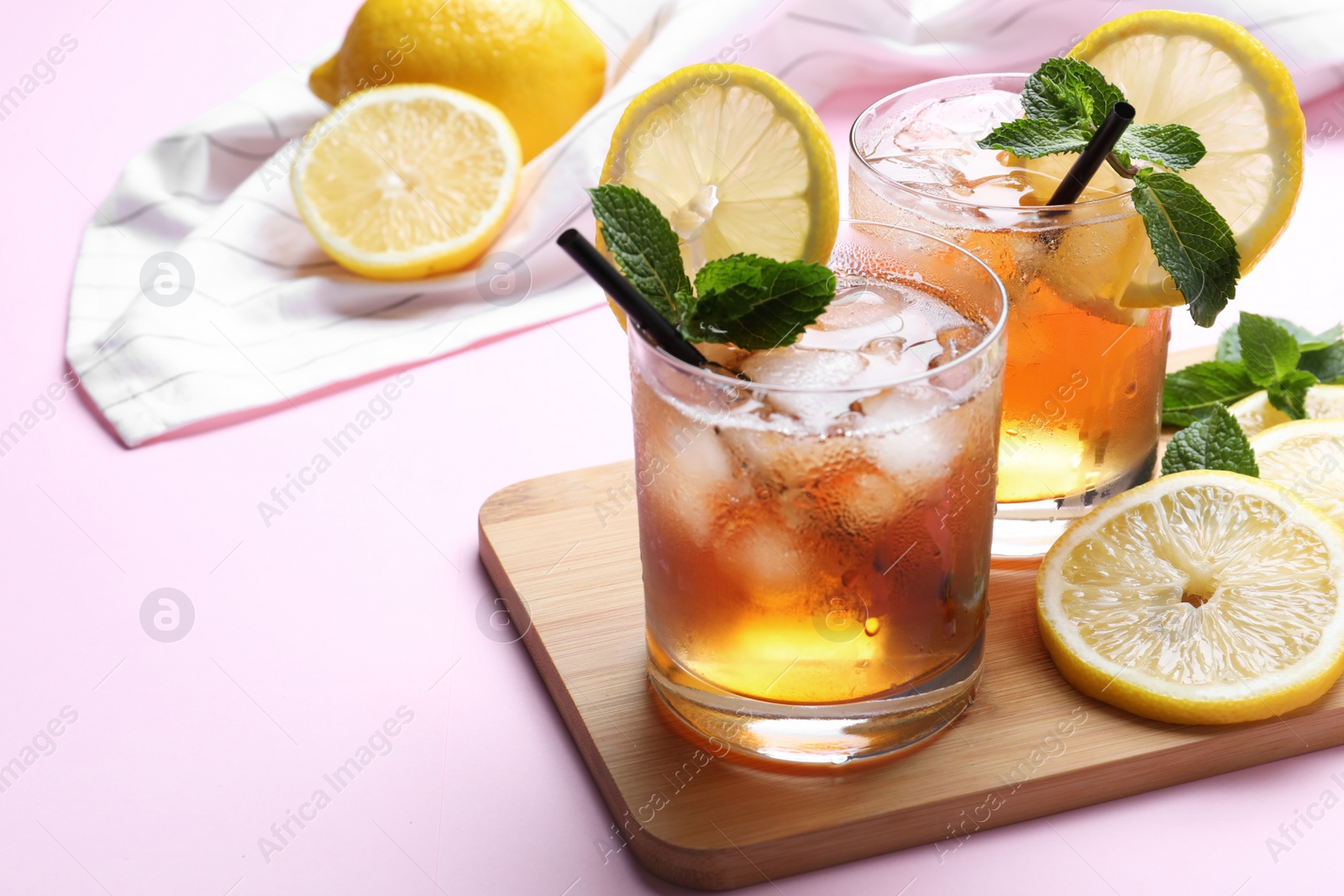 Photo of Delicious iced tea with lemon and mint on pink background, closeup