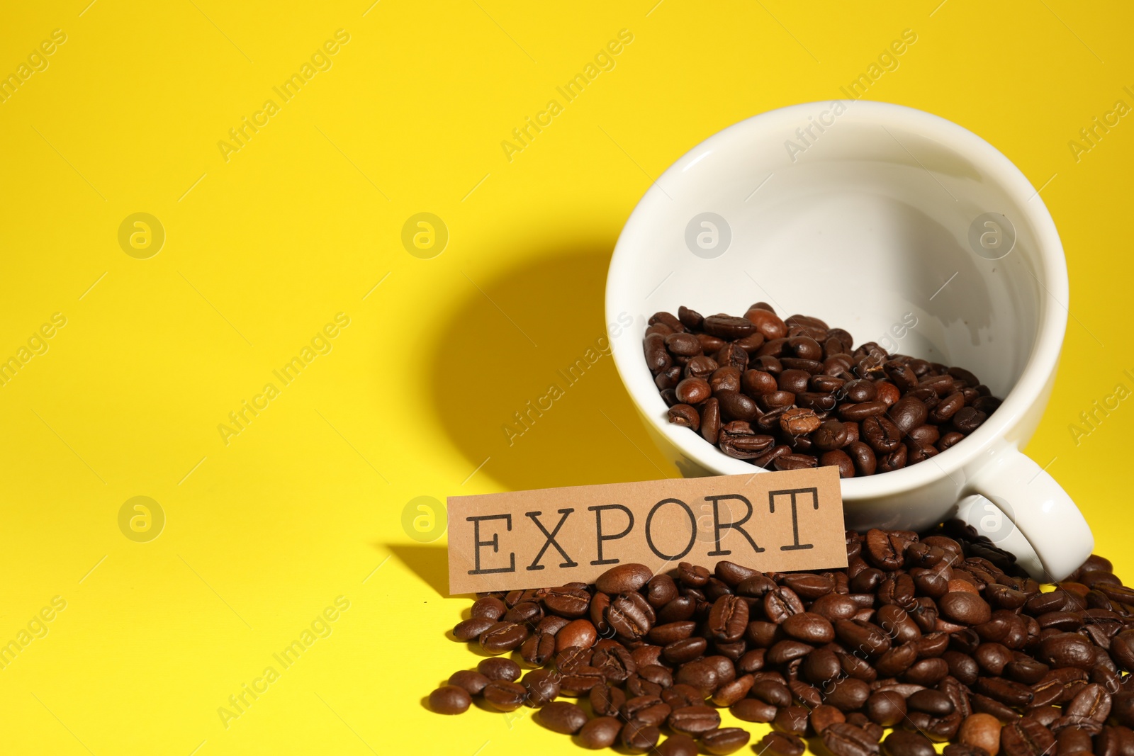 Photo of Coffee beans, white cup and card with word Export on yellow background, space for text