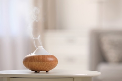 Modern essential oil diffuser on table indoors. Space for text