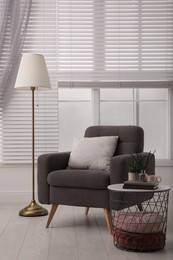 Photo of Comfortable place for rest with grey armchair near window indoors