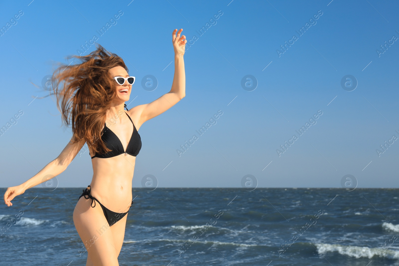 Photo of Beautiful woman in bikini on sea coast. Space for text