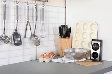 Photo of Set of clean cookware, utensils and eggs on table in modern kitchen