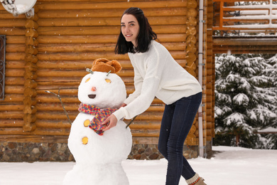 Photo of Young woman near funny snowman outdoors. Winter vacation