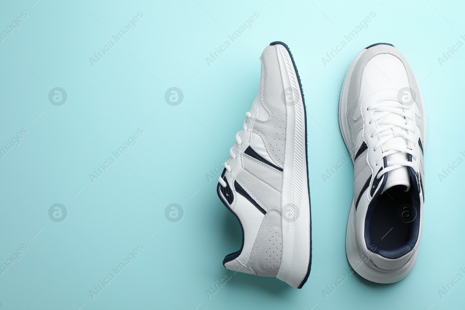 Photo of Pair of stylish sports shoes on turquoise background, flat lay. Space for text