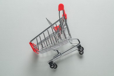 Small metal shopping cart on light background, top view