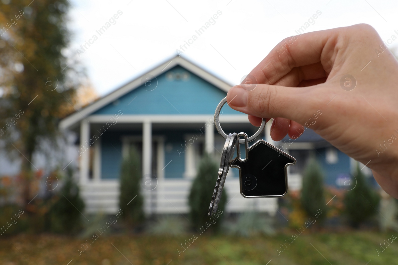 Photo of Woman holding house keys outdoors, closeup with space for text. Real estate agent