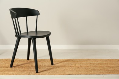 Photo of Black wooden chair near light wall in room. Space for text