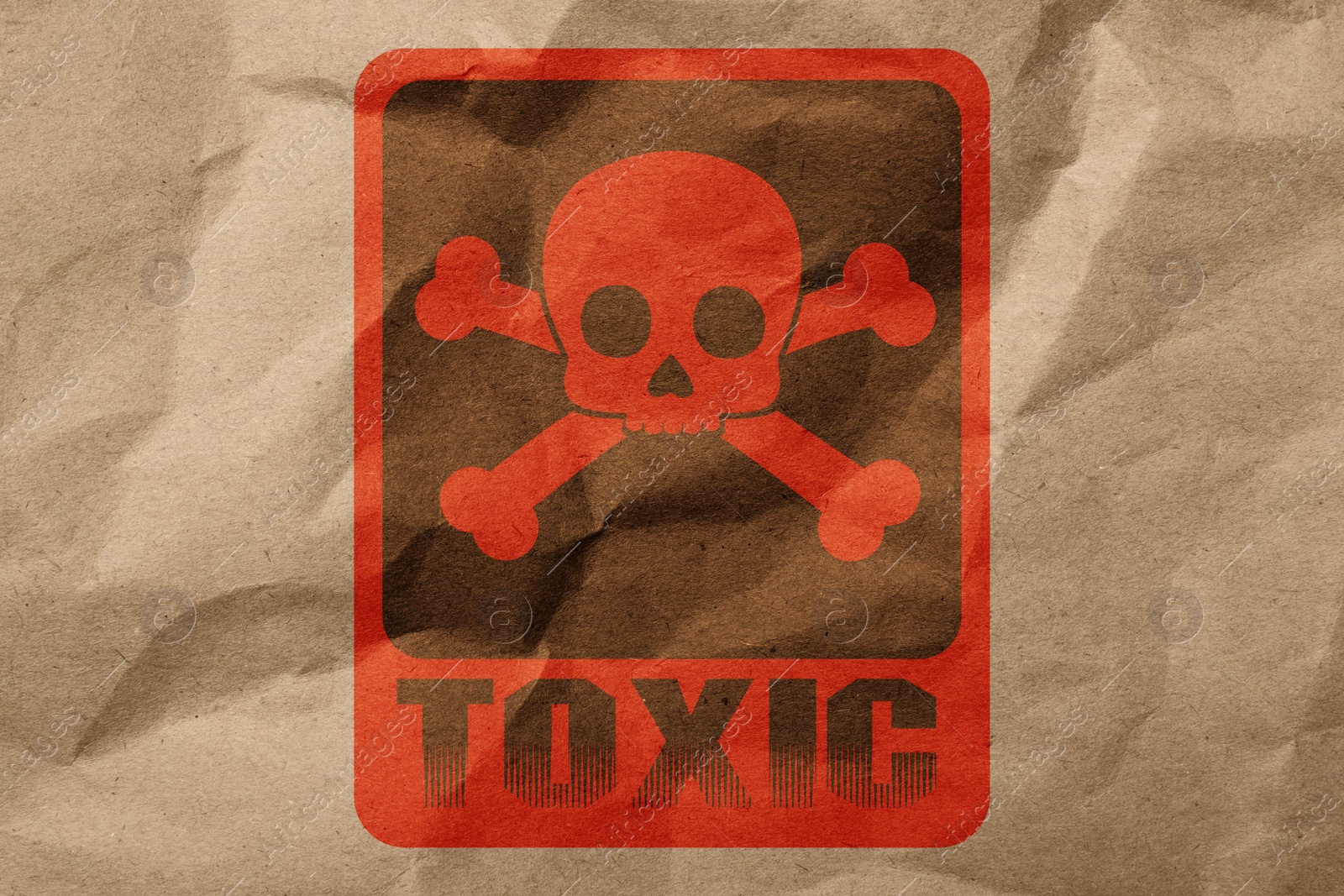 Image of Hazard warning sign (skull-and-crossbones symbol and word TOXIC) on crumpled kraft paper, top view