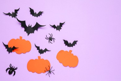 Photo of Flat lay composition with paper bats, spiders and pumpkins on light violet background, space for text. Halloween decor